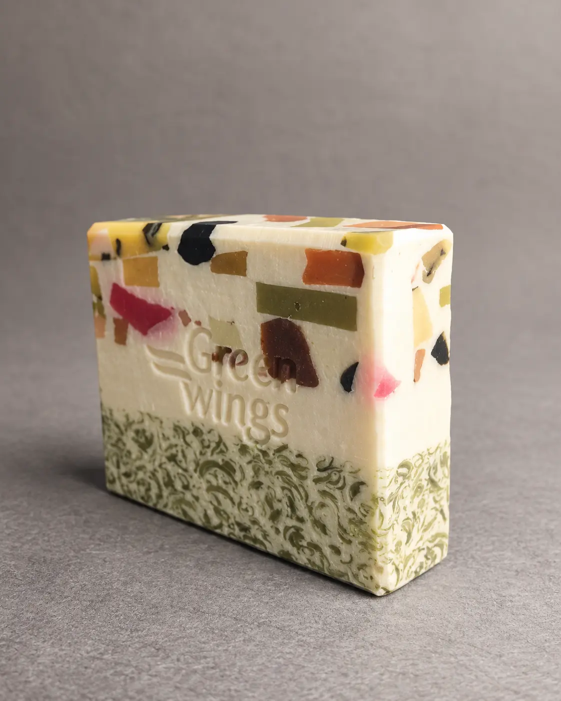A white handcrafted Greenwings soap bar with colourful botanical mosaic details