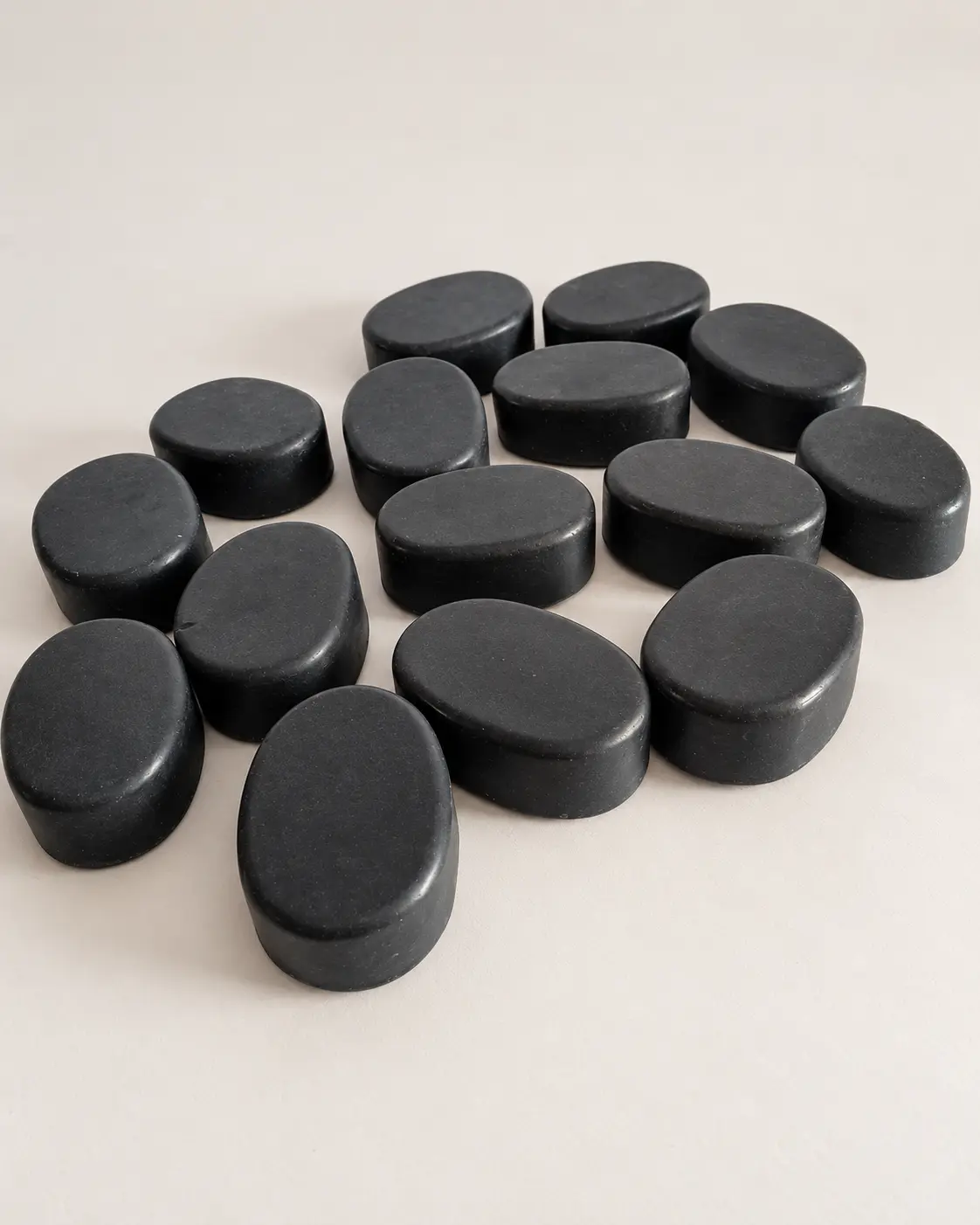 Handcrafted oval charcoal soaps arranged in the Greenwings studio